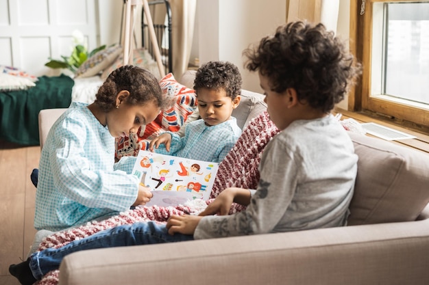 Hermanos con un libro en el sofá en casa