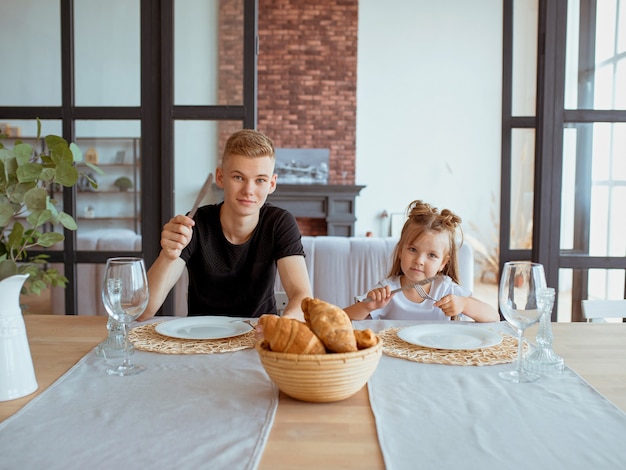 Hermanos lindos divertidos caucásicos niña con hermano mayor en el comedor en el interior de un loft moderno