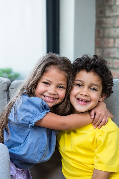 Hermanos lindos que se abrazan en el sofá