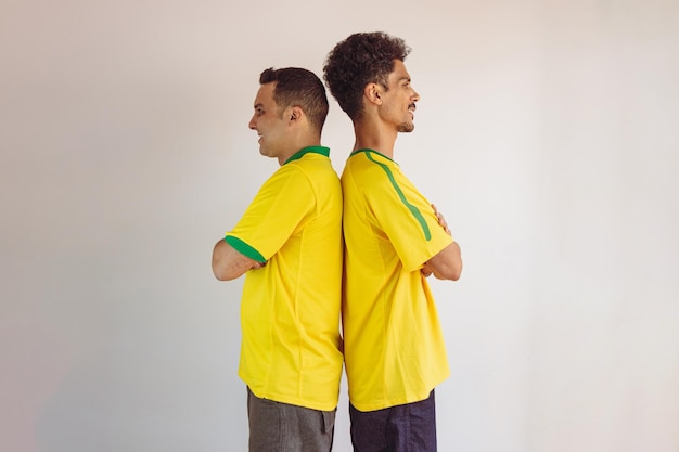 Hermanos negros con camisa brasileña amarilla y bandera animando aislados en blanco
