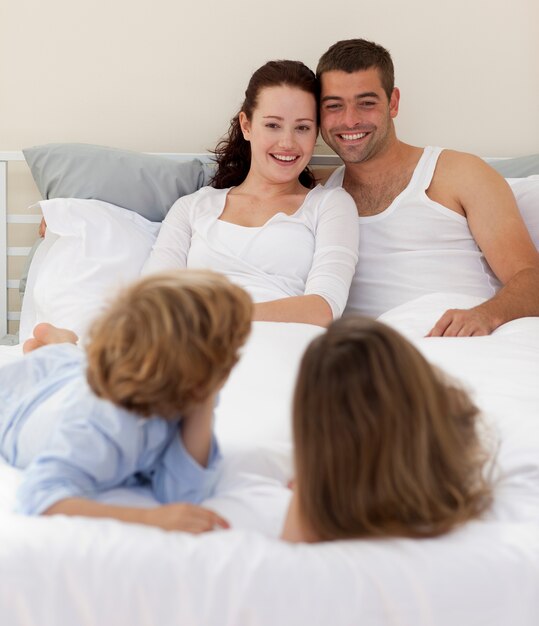 Foto hermanos y padres acostados en la cama