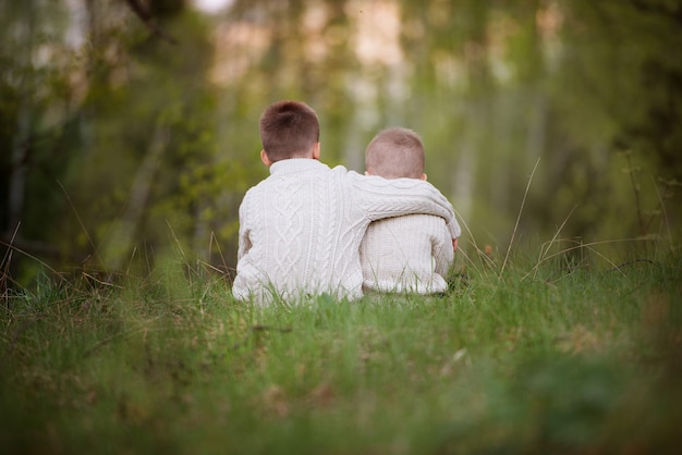 Hermanos de pie en el bosque y abrazándose.