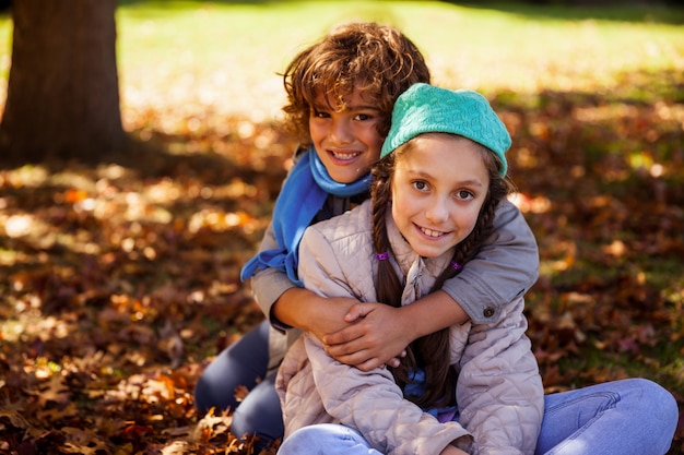 Hermanos sonrientes abrazando en el parque