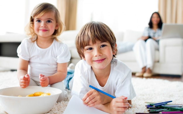 Hermanos sonrientes comiendo chips y dibujando