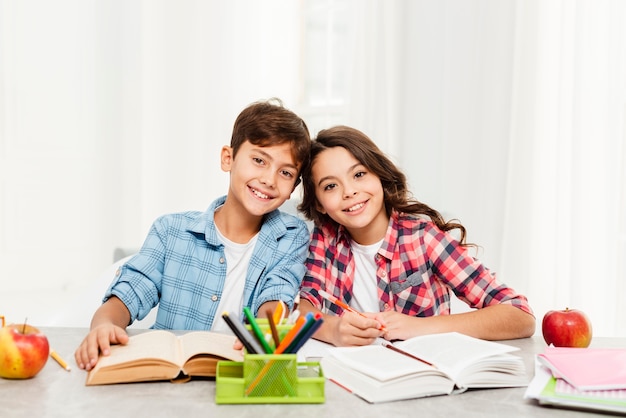 Hermanos sonrientes haciendo tareas juntos