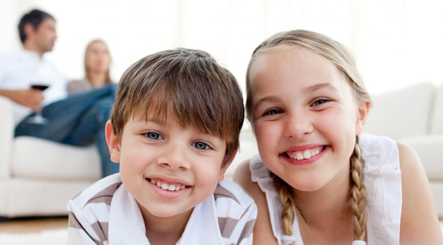 Foto hermanos sonrientes tirado en el piso