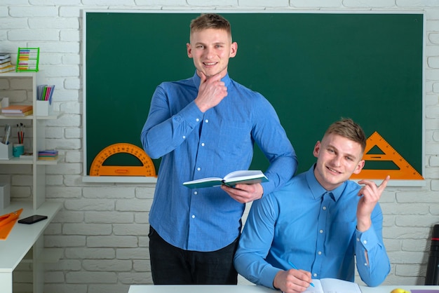 Hermanos en la universidad Gemelos estudiantes masculinos sobre la pizarra de la escuela