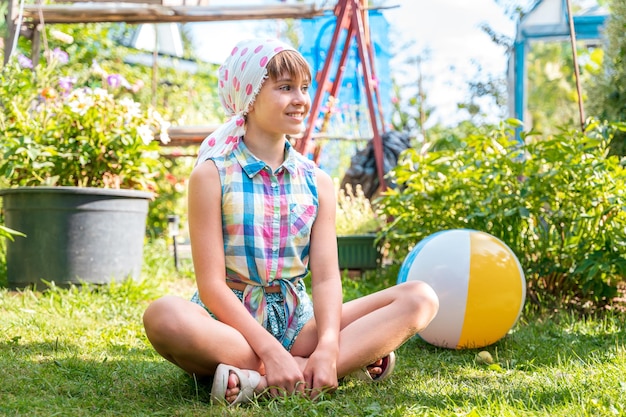 Una hermosa adolescente está descansando sobre la hierba en el jardín en verano con un ser inflable