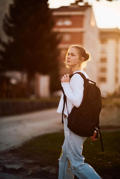 Una hermosa adolescente europea capturada en un retrato de perfil lateral camina a casa durante la puesta de sol después de