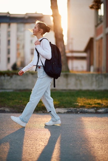 Una hermosa adolescente europea capturada en un retrato de perfil lateral camina a casa durante la puesta de sol después de