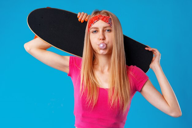 Hermosa y adolescente de moda posando con una patineta