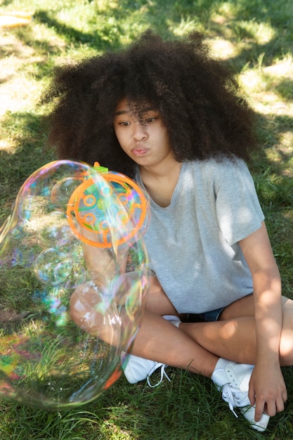 Foto hermosa adolescente negra jugando con pompas de jabón