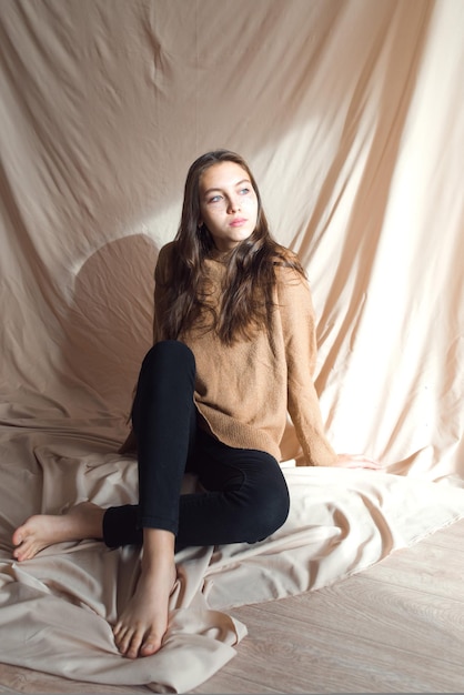 Hermosa adolescente con pecas doradas en la cara posando sobre fondo beige