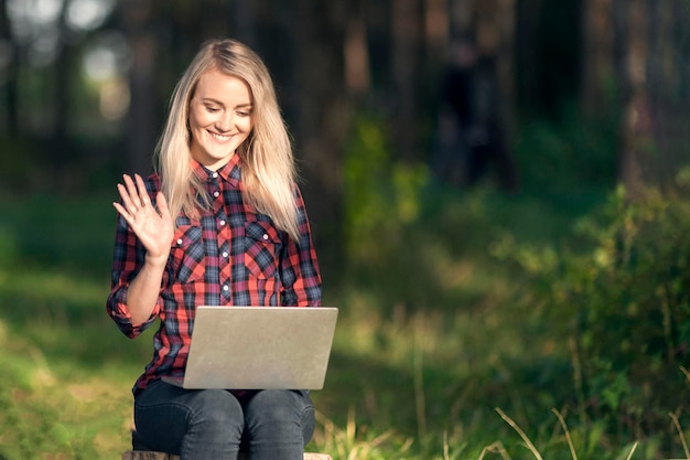 Una hermosa adolescente saluda con la mano a la cámara web en la computadora portátil