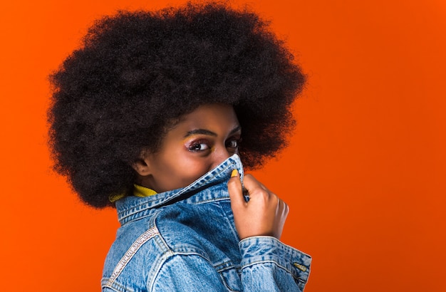 Hermosa africana cubriendo su boca con la chaqueta