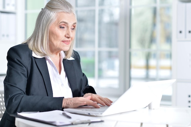 Hermosa anciana con ropa formal trabajando en una oficina moderna