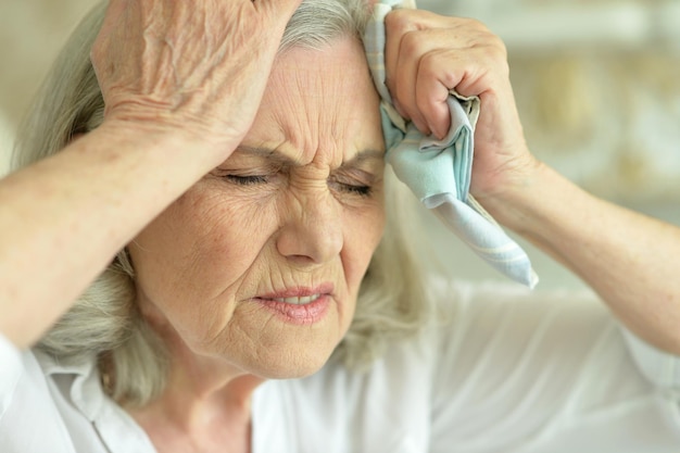 Hermosa anciana triste con dolor de cabeza en casa