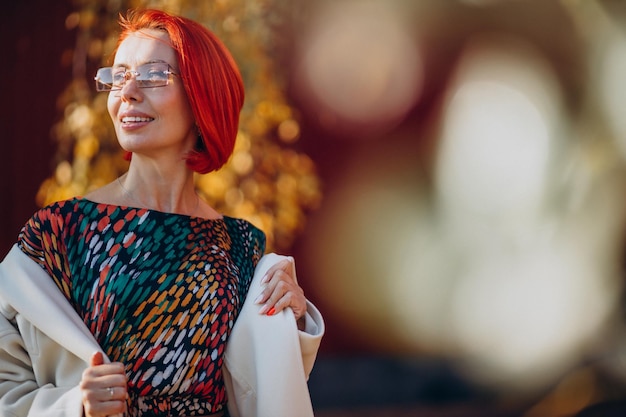 Hermosa anciana en vestido colorido fuera de la calle de otoño