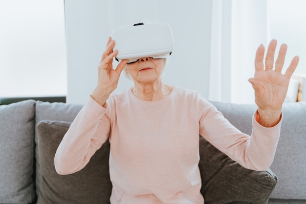 Hermosa anciana con vr googles en casa Mujer madura jugando con el mundo de realidad virtual