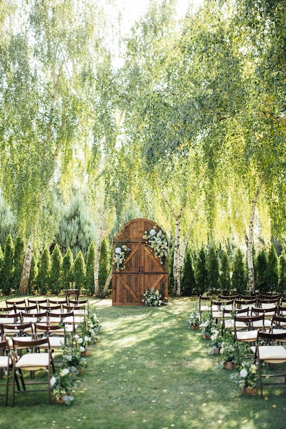 Una hermosa área para una ceremonia de boda al aire libre Arco Decorado con una gran puerta de madera con muchas flores