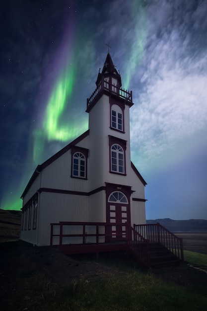 Una hermosa aurora bailando sobre una iglesia en Islandia.