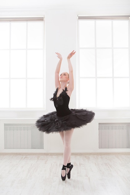 Hermosa bailarina agraciada en vestido de cisne negro. Joven bailarina de ballet practicando antes de la actuación en tutú negro, estudio de danza clásica, espacio de copia