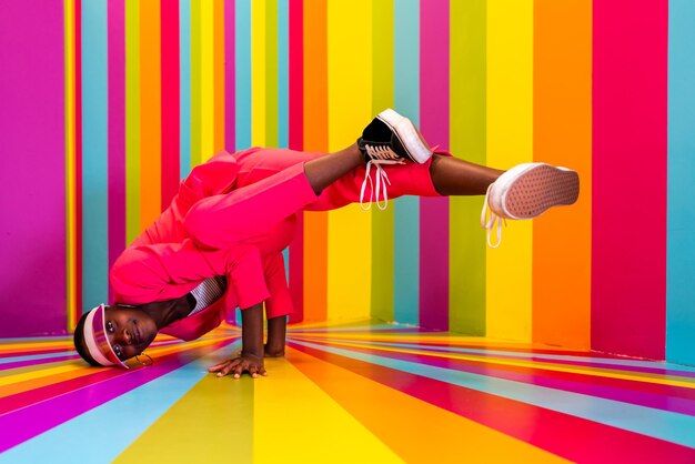 Hermosa bailarina joven afroamericana divirtiéndose dentro de una sala de caja de arco iris