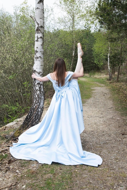 Foto hermosa bailarina en un vestido de novia azul en el fondo de un lago forestal