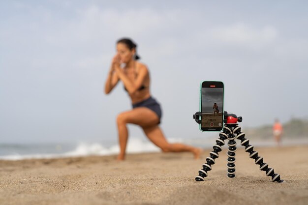 hermosa blogger de deportes se entrena en la arena y se toma fotos en un mobi