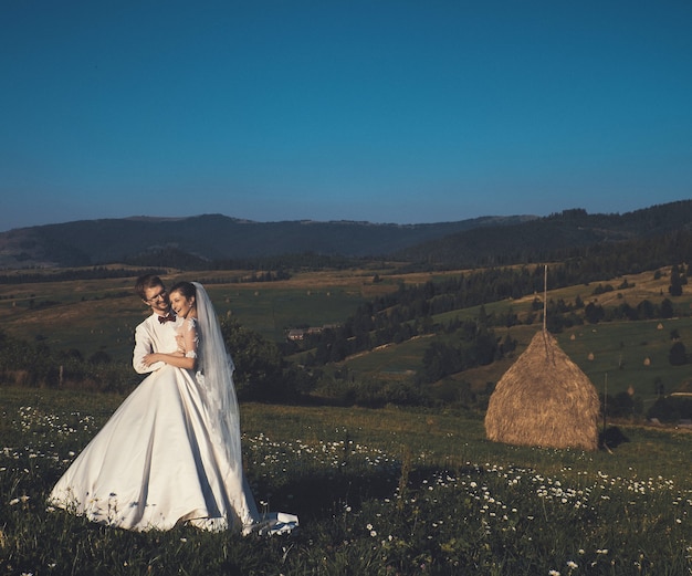 Hermosa boda en las montañas, una joven pareja feliz cerca del pajar.