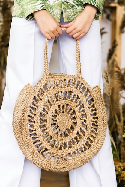 Hermosa bolsa de mimbre hecha de materiales ecológicos en manos femeninas.