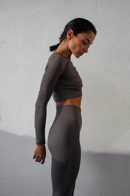 Una hermosa bruneta atlética en un traje deportivo contra una pared blanca punto de fitness deportivo estilo de vida saludable