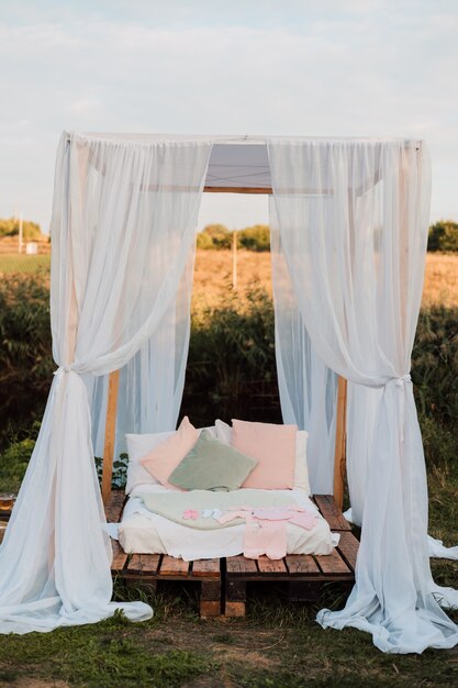 Hermosa cabaña blanca con una cama grande y almohadas en la naturaleza