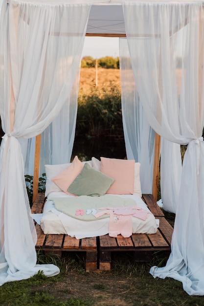 Hermosa cabaña blanca con una cama grande y almohadas en la naturaleza