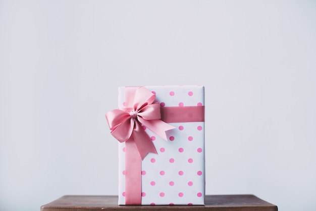 Hermosa caja de regalo con un lazo rosa sobre una mesa de madera.