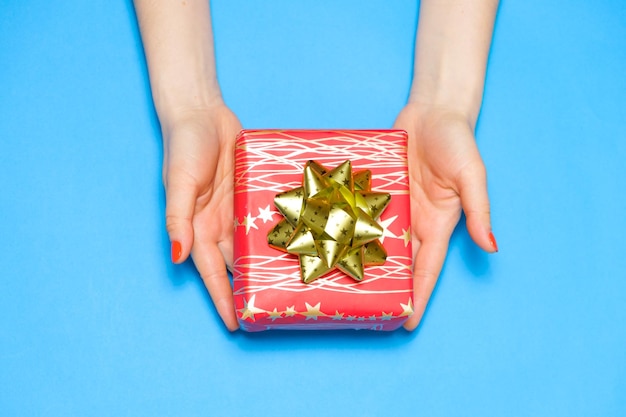 Hermosa caja de regalo roja con lazo en manos de mujeres