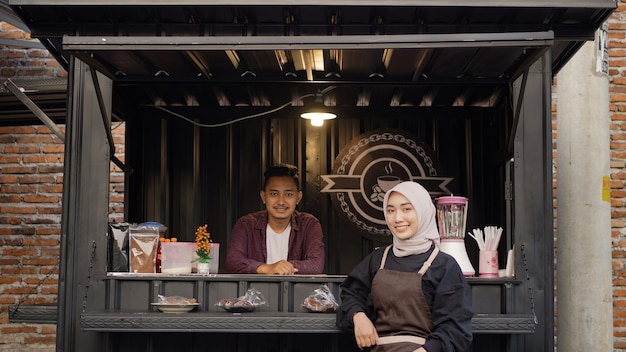 Hermosa camarera asiática y chico guapo fresco en el stand de contenedores de angkringan