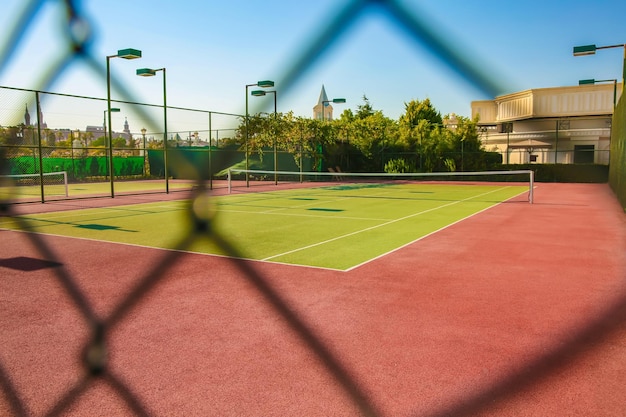 Foto hermosa cancha de tenis a la vista del día soleado a través de la valla de malla