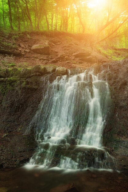 Hermosa cascada de selva tropical de montaña con agua que fluye rápidamente y rocas de larga exposición Fondo natural de viajes de temporada al aire libre con sol shihing