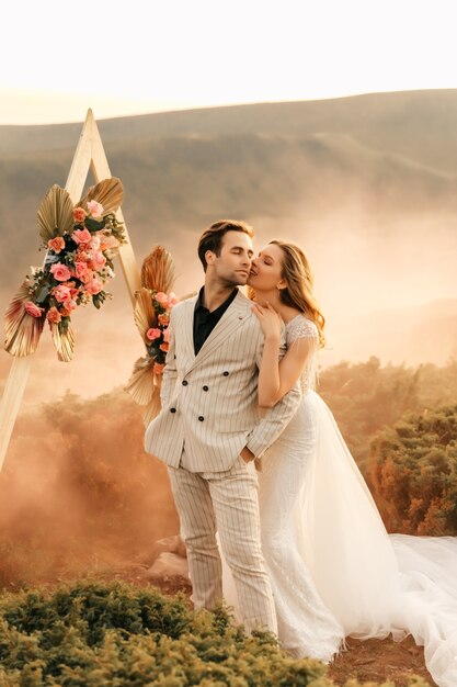 Hermosa ceremonia de boda en las montañas, novios de recién casados ?? enamorados abrazan y sonríen, boda en la naturaleza.