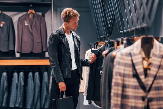 En una hermosa chaqueta negra Chico joven en una tienda moderna con ropa nueva Ropa elegante y cara para hombres