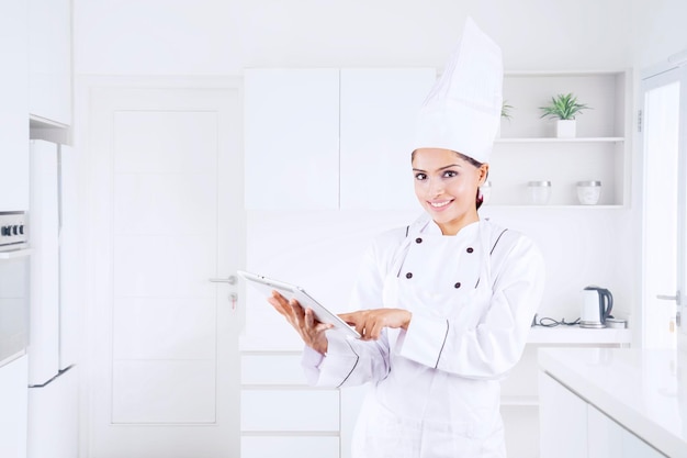 Hermosa chef usando una tableta en la cocina