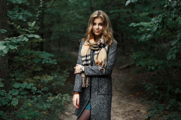 Hermosa chica con un abrigo y una bufanda en un bosque oscuro