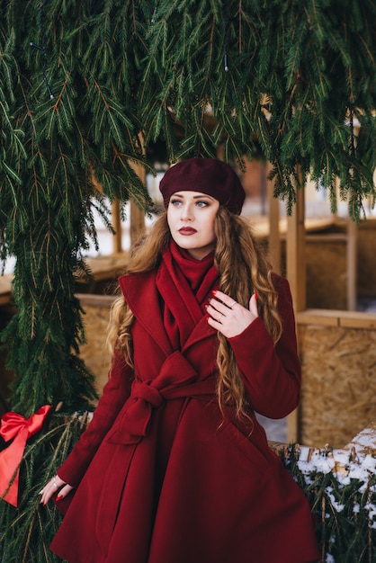 Hermosa chica con un abrigo rojo y una boina en la calle de Navidad