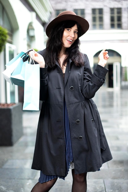 Hermosa chica con un abrigo y un sombrero disfruta de las compras