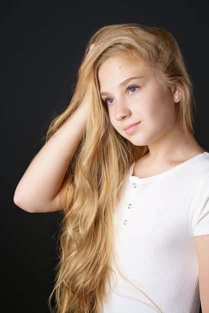 Hermosa chica adolescente con cabello largo y rubio en una camiseta blanca