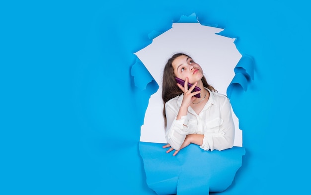 Hermosa chica adolescente hablando por teléfono. estilo de trabajo infantil. comunicación femenina. infancia feliz. niño sobre fondo azul. conversación con un amigo. mirada de moda. copie el espacio. Belleza segura.