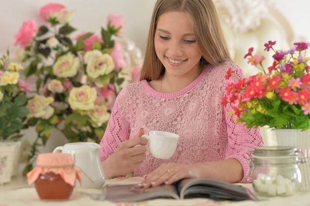 Hermosa chica adolescente leyendo una revista en casa