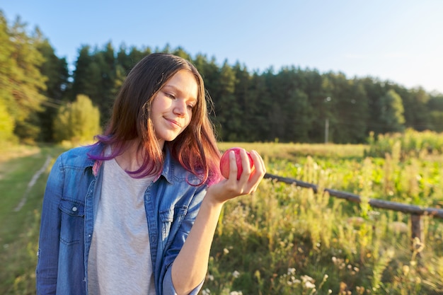 Hermosa chica adolescente con manzana roja, feliz joven en la naturaleza