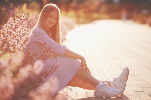 Hermosa chica adolescente sentada al aire libre en flores